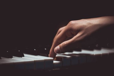 Piyanoda bir erkek el. Avuç içi tuşların üzerinde yer alır ve müzik okulunda klavyeli enstrüman çalar. öğrenci oynamayı öğrenir. eller piyanist. siyah koyu arka plan