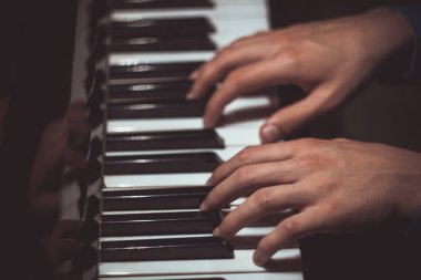 Piyanoda iki erkek eli. avuç içi tuşları üzerinde yalan ve müzik okulunda klavye liç. öğrenci oynamayı öğrenir. eller piyanist. siyah koyu arka plan. üst görünüm