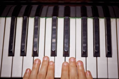 Piyanoda iki erkek eli. avuç içi tuşları üzerinde yalan ve müzik okulunda klavye liç. öğrenci oynamayı öğrenir. eller piyanist. siyah koyu arka plan. üst görünüm