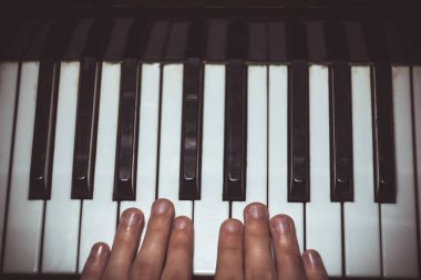 Piyanoda iki erkek eli. avuç içi tuşları üzerinde yalan ve müzik okulunda klavye liç. öğrenci oynamayı öğrenir. eller piyanist. siyah koyu arka plan. üst görünüm