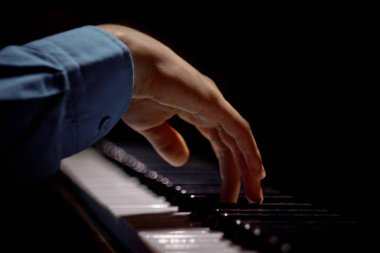 Piyanoda bir erkek el. Avuç içi tuşların üzerinde yer alır ve müzik okulunda klavyeli enstrüman çalar. öğrenci oynamayı öğrenir. eller piyanist. siyah koyu arka plan