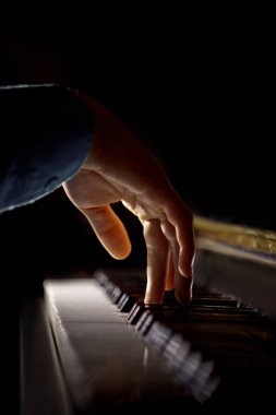 Piyanoda bir erkek el. Avuç içi tuşların üzerinde yer alır ve müzik okulunda klavyeli enstrüman çalar. öğrenci oynamayı öğrenir. eller piyanist. siyah koyu arka plan. Dikey