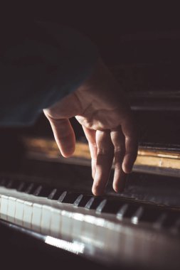 Piyanoda bir erkek el. Avuç içi tuşların üzerinde yer alır ve müzik okulunda klavyeli enstrüman çalar. öğrenci oynamayı öğrenir. eller piyanist. siyah koyu arka plan. Dikey