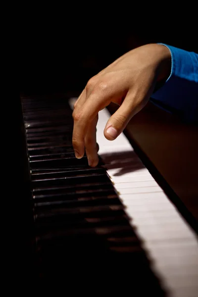 En manlig hand på pianot. Handflatan ligger på tangenterna och spelar klaviatur instrumentet i musikskolan. Eleven lär sig att spela. händer pianist. svart mörk bakgrund. Vertikala — Stockfoto