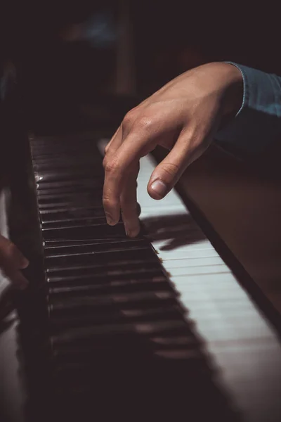 Une main masculine sur le piano. La paume repose sur les touches et joue de l'instrument à clavier dans l'école de musique. élève apprend à jouer. pianiste des mains. fond noir foncé. vertical — Photo