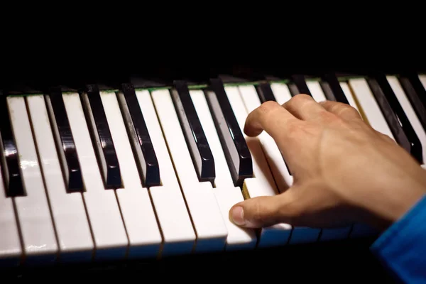 One male hand on the piano. The palm lies on the keys and plays the keyboard instrument in the music school. student learns to play. hands pianist. black dark background — Stock Photo, Image