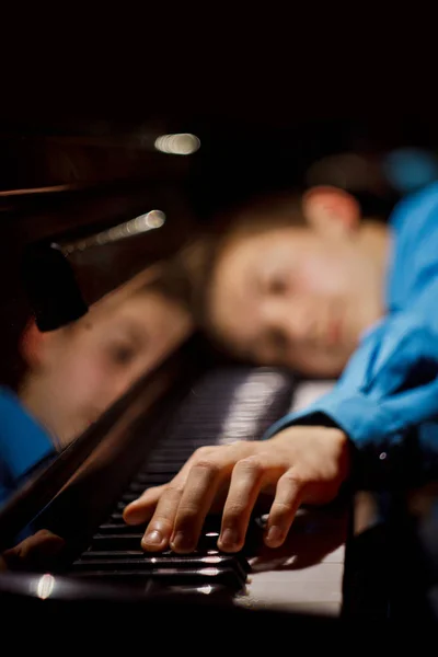 Jeune homme assis au piano. le garçon se trouve sur les touches et joue de l'instrument à clavier dans l'école de musique. élève apprend à jouer. pianiste des mains. fond noir foncé. vertical — Photo