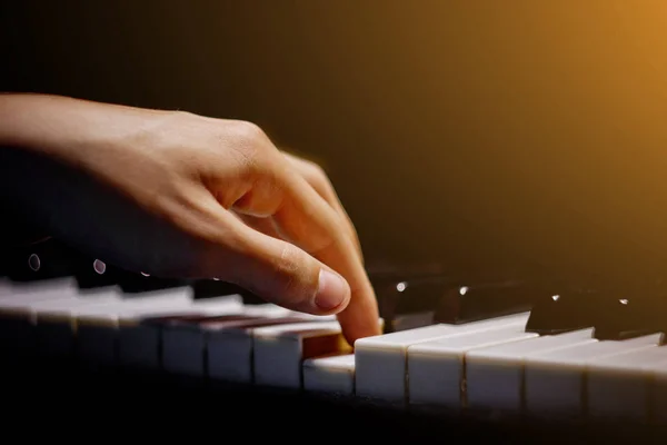 one male hand on the piano. The palm lies on the keys and plays the keyboard instrument in the music school. student learns to play. hands pianist. black dark background