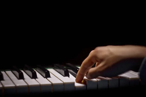 Jedna męska ręka na fortepianie. Dłoń leży na klawiszach i odgrywa instrument klawiatury w szkole muzycznej. uczeń uczy się grać. rąk pianisty. czarne ciemne tło — Zdjęcie stockowe