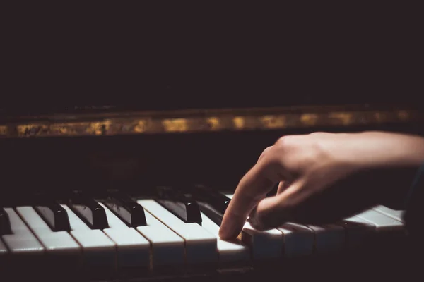 Eine männliche Hand am Klavier. Die Handfläche liegt auf den Tasten und spielt das Tasteninstrument in der Musikschule. Schüler lernt spielen. Hände Pianist. schwarzer dunkler Hintergrund — Stockfoto