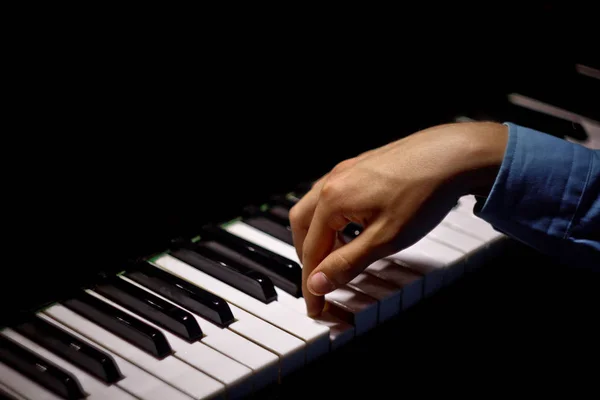 Uma mão masculina no piano. A palma da mão está nas teclas e toca o instrumento de teclado na escola de música. estudante aprende a jogar. pianista de mãos. preto escuro fundo — Fotografia de Stock