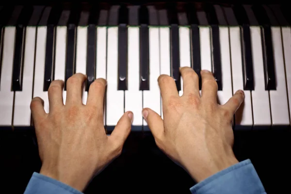 Deux mains masculines sur le piano. palms se trouvent sur les touches et jouent de l'instrument à clavier dans l'école de musique. élève apprend à jouer. pianiste des mains. fond noir foncé. vue de dessus — Photo