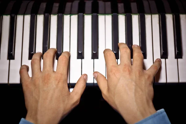 Deux mains masculines sur le piano. palms se trouvent sur les touches et jouent de l'instrument à clavier dans l'école de musique. élève apprend à jouer. pianiste des mains. fond noir foncé. vue de dessus — Photo