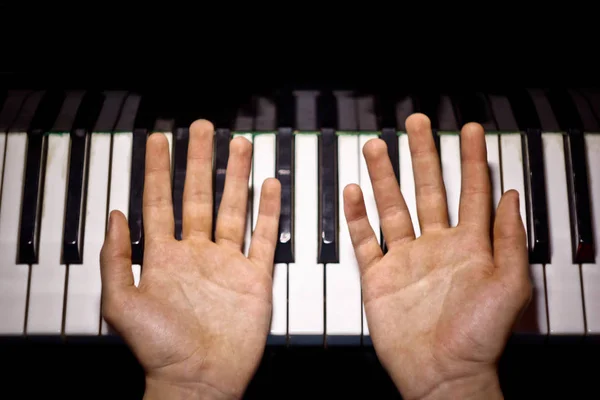 Deux mains masculines sur le piano. palms se trouvent sur les touches et jouent de l'instrument à clavier dans l'école de musique. élève apprend à jouer. pianiste des mains. fond noir foncé. vue de dessus — Photo