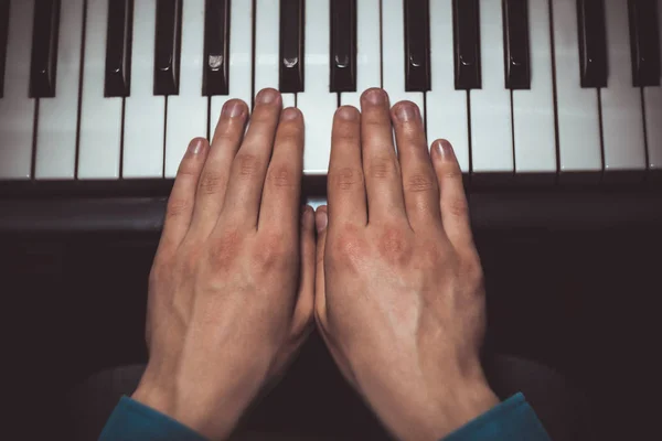 Dwóch męskich rąk na fortepianie. dłonie leżą na klawiszach i odgrywają instrument klawiatury w szkole muzycznej. uczeń uczy się grać. rąk pianisty. czarnym ciemnym tle. Widok z góry — Zdjęcie stockowe