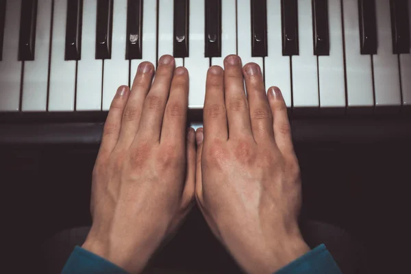 Dos manos masculinas en el piano. las palmas yacen en las teclas y tocan el instrumento de teclado en la escuela de música. estudiante aprende a jugar. manos pianista. fondo negro oscuro. vista superior — Foto de Stock