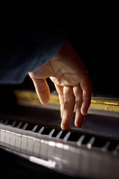 One male hand on the piano. The palm lies on the keys and plays the keyboard instrument in the music school. student learns to play. hands pianist. black dark background. vertical — Stock Photo, Image