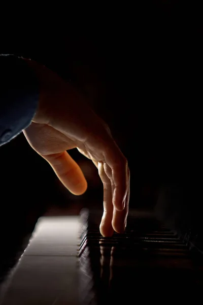 ピアノに一人の男性の手。手のひらはキーの上にあり、音楽学校のキーボード楽器を演奏します。学生は遊ぶことを学ぶ。手のピアニスト。黒い暗い背景。垂直 — ストック写真