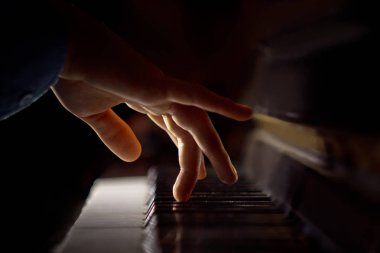 Piyanoda bir erkek el. Avuç içi tuşların üzerinde yer alır ve müzik okulunda klavyeli enstrüman çalar. öğrenci oynamayı öğrenir. eller piyanist. siyah koyu arka plan