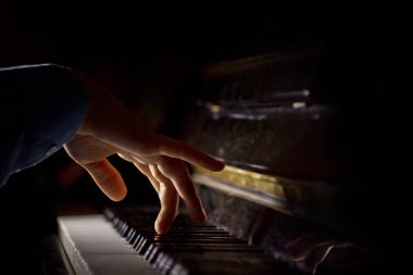 Piyanoda bir erkek el. Avuç içi tuşların üzerinde yer alır ve müzik okulunda klavyeli enstrüman çalar. öğrenci oynamayı öğrenir. eller piyanist. siyah koyu arka plan