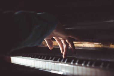 Piyanoda bir erkek el. Avuç içi tuşların üzerinde yer alır ve müzik okulunda klavyeli enstrüman çalar. öğrenci oynamayı öğrenir. eller piyanist. siyah koyu arka plan
