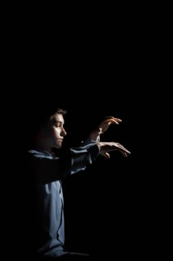 Genç adam piyanonun başında oturuyor. Erkek çocuk müzik okulunda klavye enstrümanı çalıyor. Öğrenci çalmayı öğreniyor. Eller piyanist. Siyah siyah arka plan. dikey