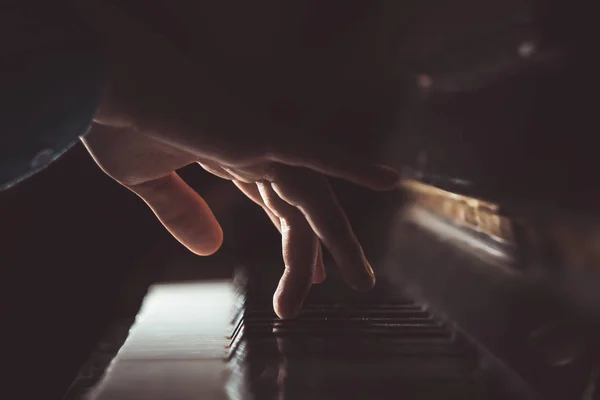 Una mano masculina en el piano. La palma se encuentra en las teclas y toca el instrumento de teclado en la escuela de música. estudiante aprende a jugar. manos pianista. fondo negro oscuro — Foto de Stock
