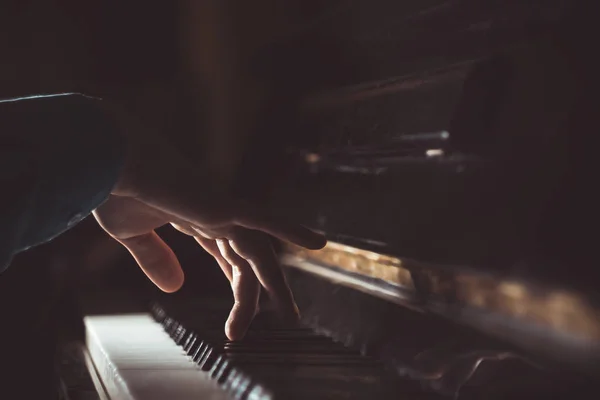 Eine männliche Hand am Klavier. Die Handfläche liegt auf den Tasten und spielt das Tasteninstrument in der Musikschule. Schüler lernt spielen. Hände Pianist. schwarzer dunkler Hintergrund — Stockfoto