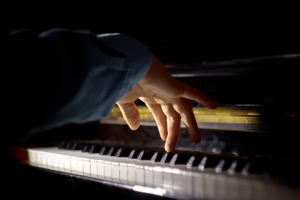 Une main masculine sur le piano. La paume repose sur les touches et joue de l'instrument à clavier dans l'école de musique. élève apprend à jouer. pianiste des mains. fond noir foncé — Photo