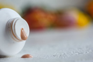krem ve beyaz bir masada açık kapak yakın çekim ile plastik ağız tüp. bulanık bir arka plan üzerinde vücut bakımı yakın çekim için kozmetik