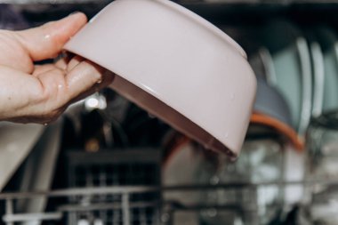 Dişi el temiz, yıkanmış bulaşıkları tıkalı açık bir bulaşık makinesi yakın çekim bulaşık makinesinde tabaklar koyar. kuru çatal bıçak takımı yakın çekim. kaşık çatal. kupalar, tabaklar. mutfakta ev aletleri