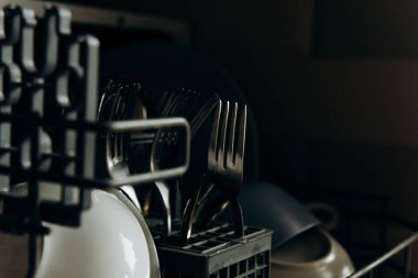 açık bulaşık makinesi, temiz yıkanmış bulaşıklarla tıkanmış kapatın. kuru çatal bıçak takımı yakın çekim. kaşık çatal. kupalar, tabaklar. mutfakta ev aletleri