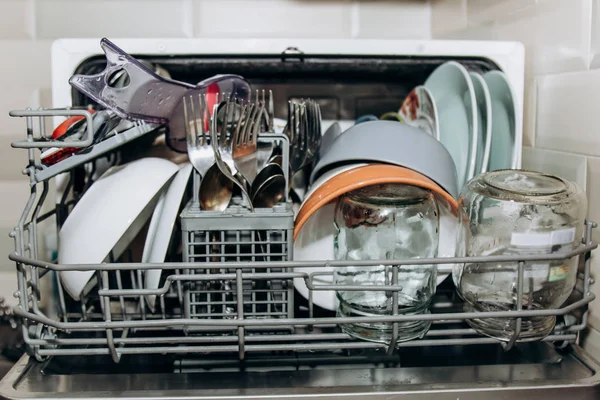 Nyitott mosogatógép közelről eltömődött tiszta mosott ételeket. száraz evőeszköz-closeup. kanál Villa. bögrék, lemezek. háztartási készülékek a konyhában — Stock Fotó