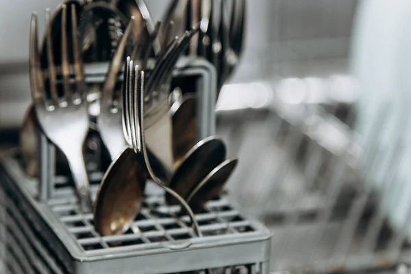 Trockene Gabeln und Löffel in einer offenen Spülmaschine reinigen. Besteckabteil aus nächster Nähe. Haushaltsgeräte in der Küche — Stockfoto