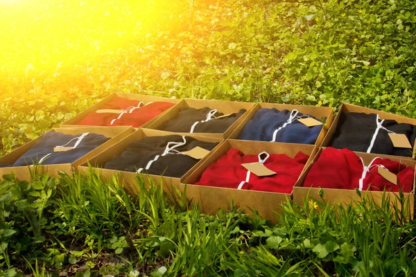 골판지 상자에 접힌 태그가있는 다채로운 스포츠웨어는 잔디로 땅에 놓여 있습니다. 포장 된 의류 상단보기. 포장 해제 구매 — 스톡 사진