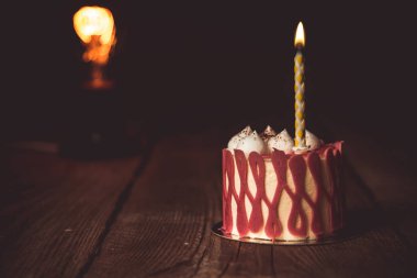 koyu bir arka plan üzerinde rustik ahşap masada kiraz meyve ile şenlikli bir pasta pasta bir yanan mum. kopyalama alanını kapatın. tatlı tartlet üzerinde vintage desen. doğum günü tatili