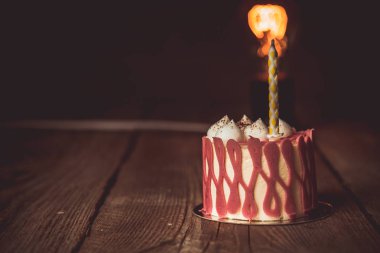 koyu bir arka plan üzerinde rustik ahşap masada kiraz meyve ile şenlikli bir pasta pasta bir yanan mum. kopyalama alanını kapatın. tatlı tartlet üzerinde vintage desen. doğum günü tatili