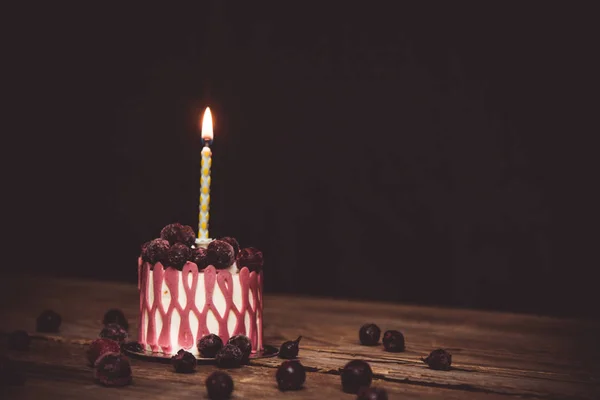 暗い背景に素朴な木製のテーブルの上にチェリーフルーツとお祝いのケーキで1燃えるキャンドル。コピースペースをクローズアップします。デザートタルトレットのヴィンテージパターン。誕生日の休日 — ストック写真