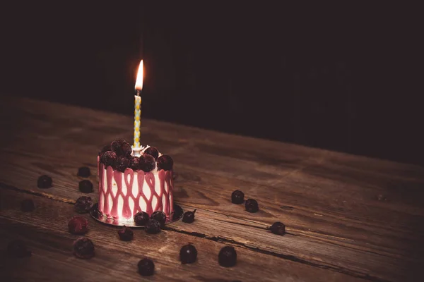 Egy égő gyertya ünnepi torta torta cseresznye gyümölcsök egy rusztikus fából készült asztal, sötét háttér. közelíti a másolási lemezterületet. Vintage minta a desszert tartlet. születésnapi üdülés — Stock Fotó