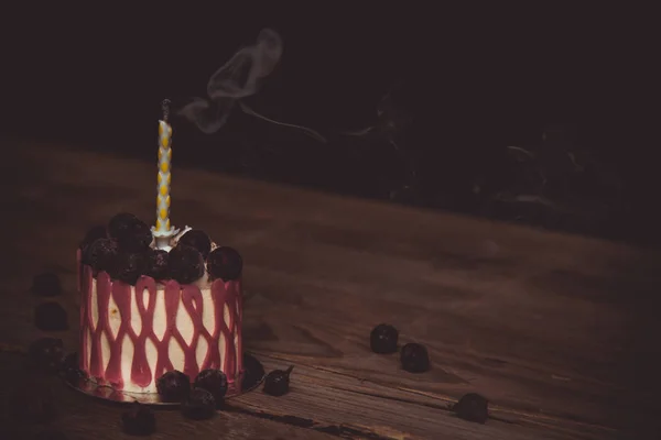 Karanlık bir arka plan üzerinde rustik ahşap bir masa üzerinde kiraz meyveile şenlikli bir pasta bir söndürüldü mum. kopyalama alanını kapatın. tatlı tartlet üzerinde vintage desen. doğum günü tatili — Stok fotoğraf