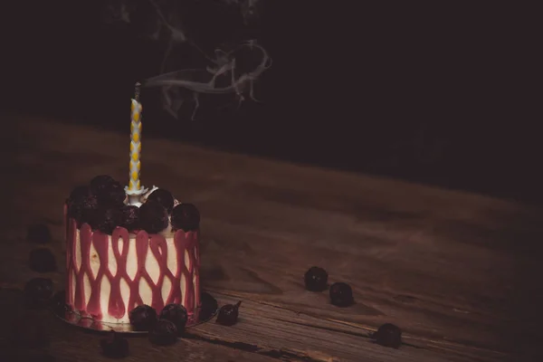 Una vela apagada en un pastel festivo con los frutos de la cereza sobre una mesa de madera rústica sobre un fondo oscuro. cerrar espacio de copia. patrón vintage en tartaleta de postre. vacaciones de cumpleaños —  Fotos de Stock