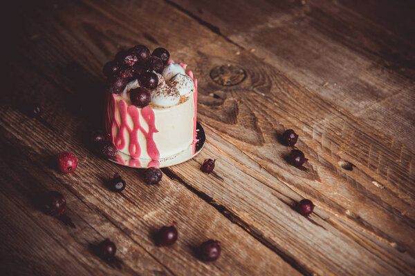 festive cake with the fruits of cherry on a rustic wooden table on a dark background. close up copy space. vintage pattern on dessert tartlet. birthday holiday