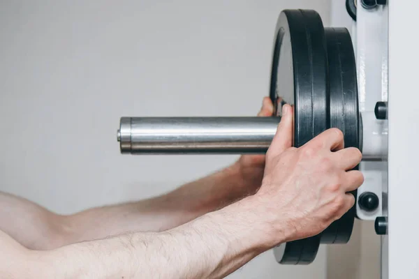大手的运动员通过金属盘增加重量到训练中心的训练仪器。健身房特写训练器材 — 图库照片