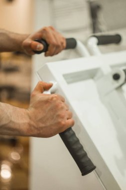 Atlet eğitim merkezinde eğitim makinesinin kabzaellerini tutar. spor salonunda yakın çekim eğitim araçları