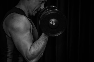 atlet siyah bir arka plan üzerinde egzersiz merkezinde dumbbells ile pazı elleri drenaj. spor salonunda yakın çekim eğitim araçları