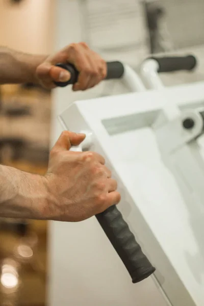 Hält der Athlet seine Hände am Griff des Trainingsgeräts im Trainingszentrum. Trainingsgeräte in der Turnhalle aus nächster Nähe — Stockfoto