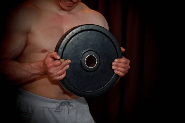 Sportovci trénují biceps s činkami uprostřed cvičení na černém pozadí. školicí nástroje v posilovně zblízka — Stock fotografie