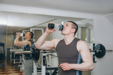 atlet eğitim merkezinde bir shaker su içiyor. spor salonunda egzersizler arasında dinlenme
