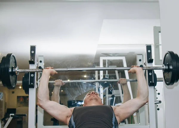 Idrottare skakar bröstmusklerna i mitten av utbildningen. Övning bröst press. träningsredskap i gymmet närbild — Stockfoto