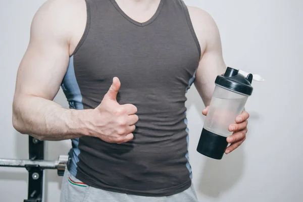 The athlete drinks water from a shaker in the training center. rest between exercises in the gym — Stock Photo, Image